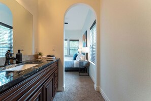 A narrow hallway with a bathroom on the right, featuring a sink, mirror, and towel rack. - Relax & Play in Style: Luxury Home w/ Infinity Pool, Game Room & Alfresco Dining (Jonestown)