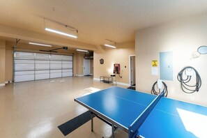 A spacious indoor area with a ping pong table, a garage door, and a fire extinguisher.