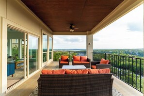 A balcony with wicker furniture and a view of a river.