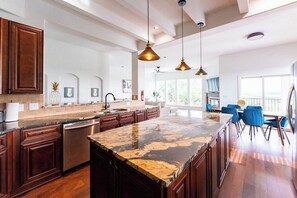 A spacious kitchen with dark wood cabinets, a granite countertop, and pendant lighting.