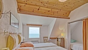 Ein Schlafzimmer mit zwei Betten, einer Holzbalkendecke, einem Fenster mit Blick und einem kleinen Tisch mit Lampe.
