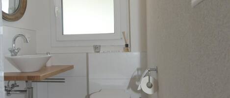A compact bathroom with a toilet, sink, and mirror.