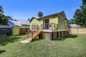 Uma casa amarela com uma escada de madeira que dá para um deck.
