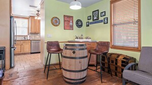 Una cucina con mobili in legno, uno sgabello da bar, una botte di legno e un'area pranzo con una panca.