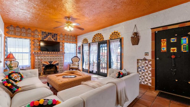 A living room with a fireplace, white sofas, and a TV. - The Gaudi House- Pool/Minutes to DNTN and Beach (St. Augustine)