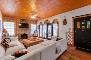 Una sala de estar con chimenea, sofás blancos y televisor.