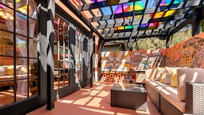 A sunlit patio area with wicker furniture, patterned wall tiles, and large windows. - The Gaudi House- Pool/Minutes to DNTN and Beach (St. Augustine)