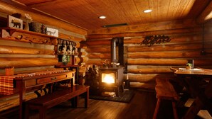 A cozy log cabin interior with a wooden bench, a table, a fireplace, and wall-mounted decorations. - Log Cabin Hot Tub Getaway (Walhonding)