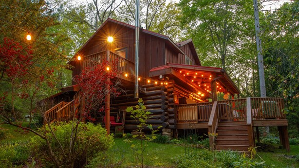 A log cabin with a wooden deck and a staircase leading to a porch. - Log Cabin Hot Tub Getaway (Walhonding)