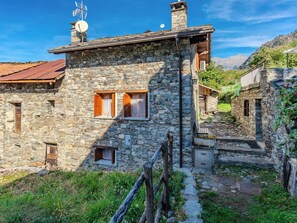 A stone building with multiple windows and a wooden staircase leading to a second level.