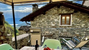 Ein Steinhaus mit einem Fenster und einem Tisch für zwei, gedeckt mit einer Weinflasche und einer Blume.