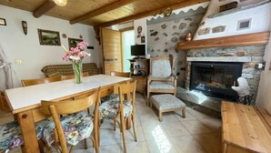 Ein gemütlicher Essbereich mit Holztisch und Stühlen, einem Blumenstrauß und einem Kamin aus Stein.
