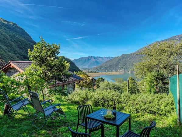 A serene outdoor seating area with a table and chairs, overlooking a lake and mountains. - Vacation home Maria by Interhome (Lago di Mezzola)
