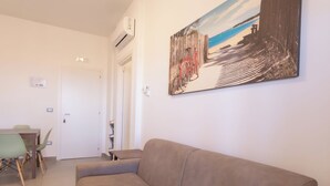 Un salon avec un canapé beige, une table à manger avec des chaises et un tableau accroché au mur.