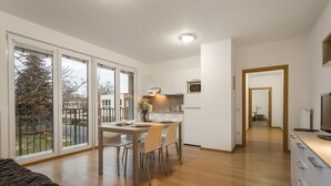 En moderne lejlighed med spiseplads, køkken og en stor skydedør, der fører ud til en balkon.