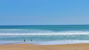 A beach with a clear sky, calm sea, and two people near the water's edge. - Direct Oceanfront Townhome with Breathtaking Views of the Beach (New Smyrna Beach)