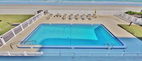 A rectangular pool with a white deck and a white fence.