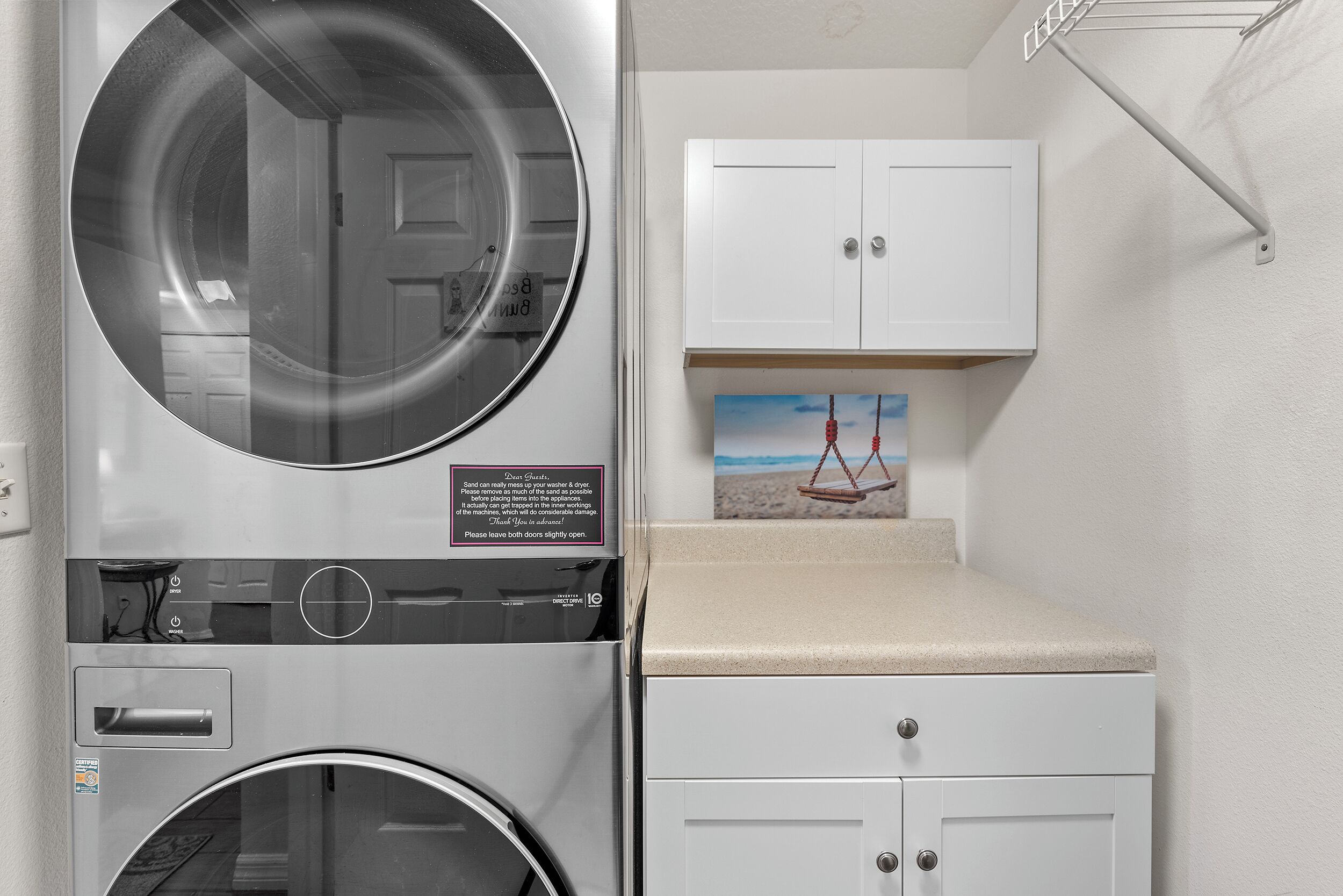 A laundry area with a washing machine, dryer, and a cabinet with a picture of a swing set.