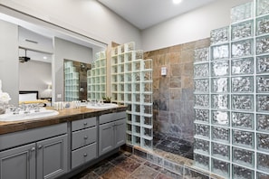 Un bagno moderno con doppio lavabo, uno specchio grande e cabina doccia in vetro.
