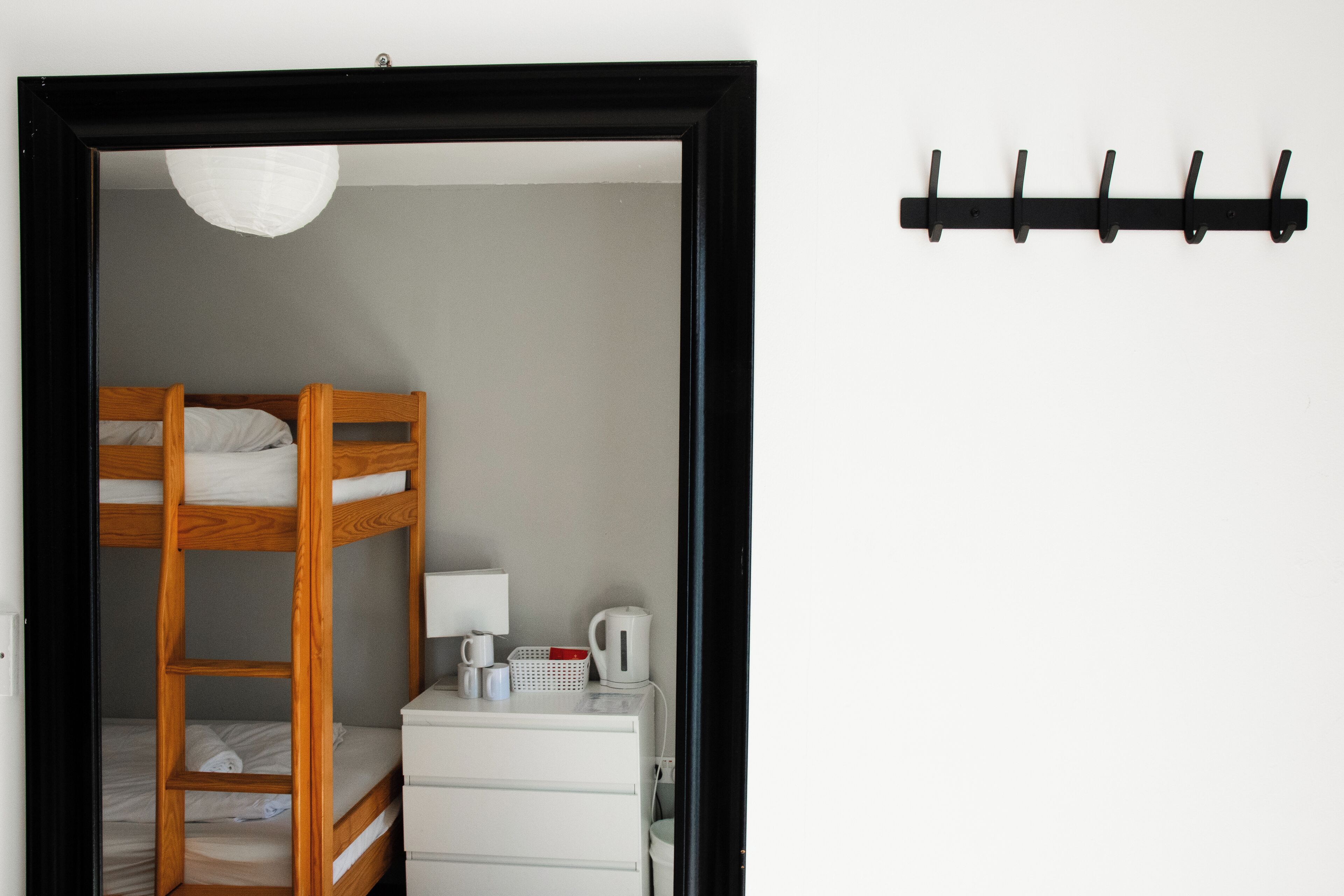 Ein Schlafraum mit Etagenbetten, einem weißen Schminktisch und einem Haken an der Wand.