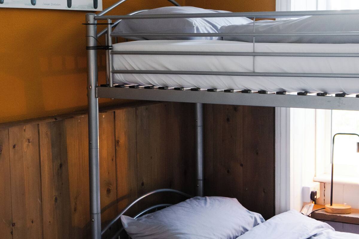 Une chambre avec un lit superposé, un mur en bois et une affiche de voitures.