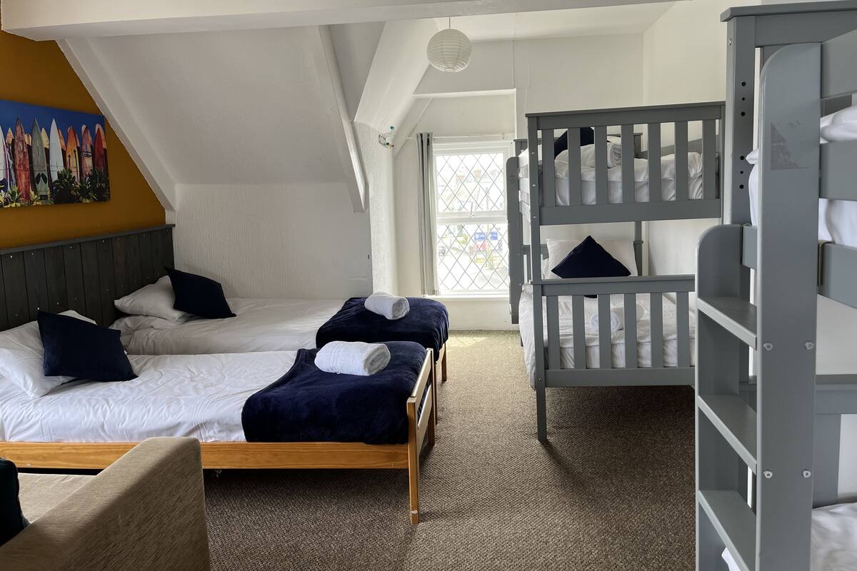 Une chambre avec deux lits, dont un avec un cadre en bois et l’autre avec un lit superposé.