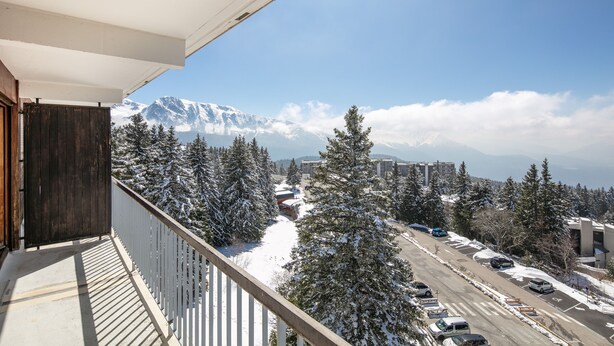 Ein Balkon mit Blick auf einen verschneiten Berg und einen Parkplatz.