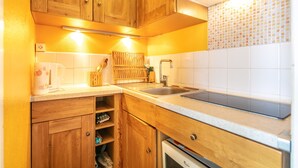 Eine kompakte Küche mit Holzausstattung, integriertem Backofen und gefliestem Rücksprung.