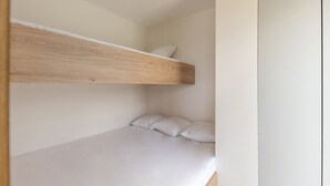 Una cama litera con cabecera de madera y ropa de cama blanca.