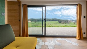 Una habitación con un gran ventanal corredero que da a un paisaje verde.