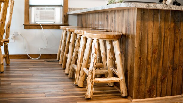 Una cocina con taburetes de madera, una encimera de madera y una ventana con aire acondicionado.