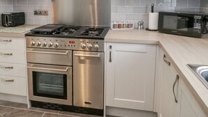 Une cuisine moderne dotée d’appareils électroménagers en acier inoxydable, de meubles blancs et d’un four encastré.
