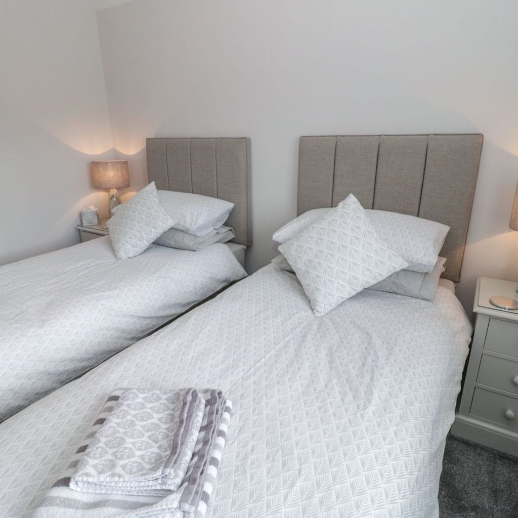A twin room with two beds, each with a headboard, and bedside tables with lamps.