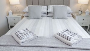 Un lit bien fait, avec une literie à rayures, deux tables de chevet avec des lampes et une tête de lit.