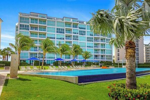 Um hotel com piscina, palmeiras e fachada de edifício moderna.