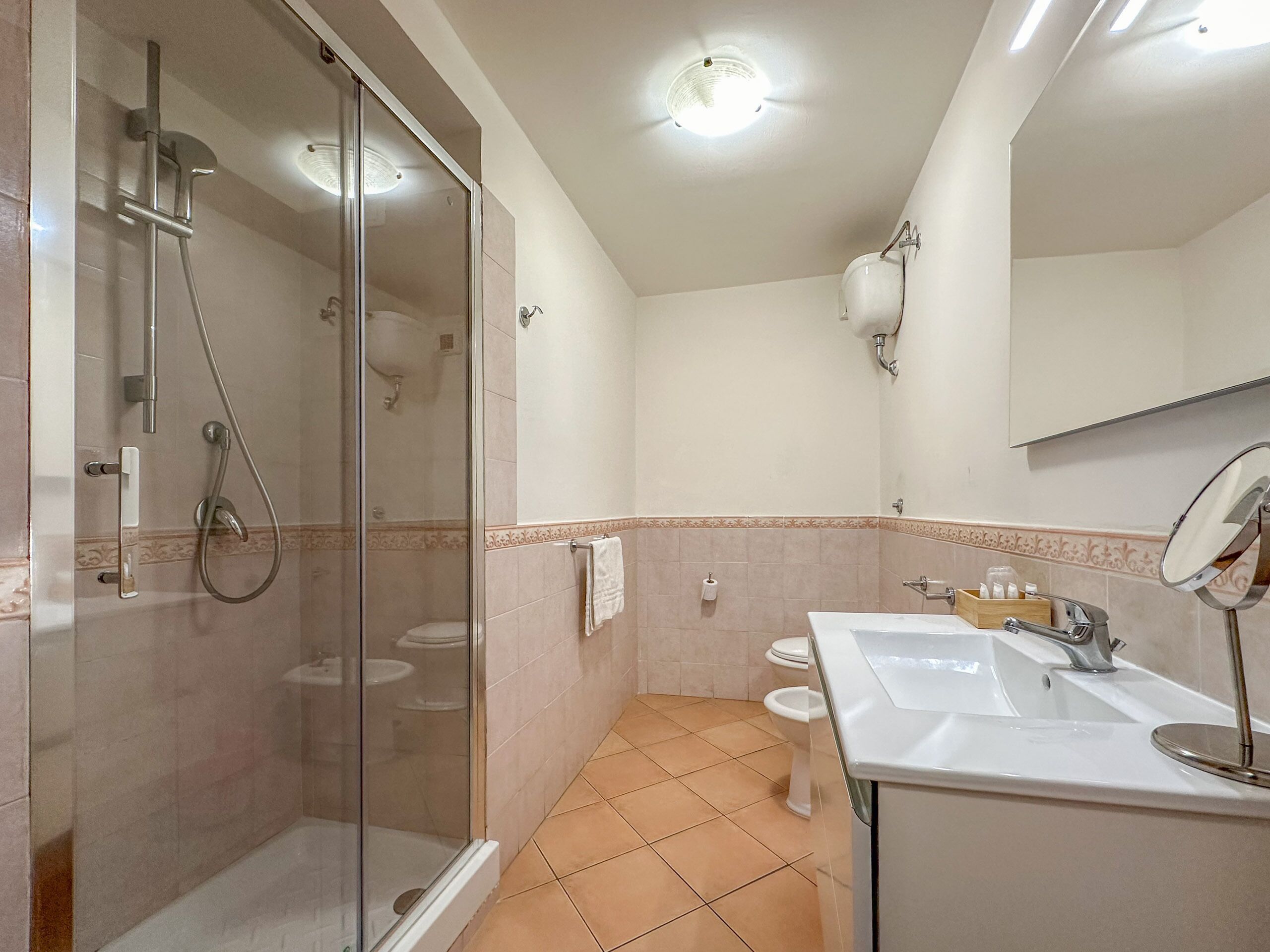 A bathroom with a glass-enclosed shower, a sink with a mirror, and a toilet.