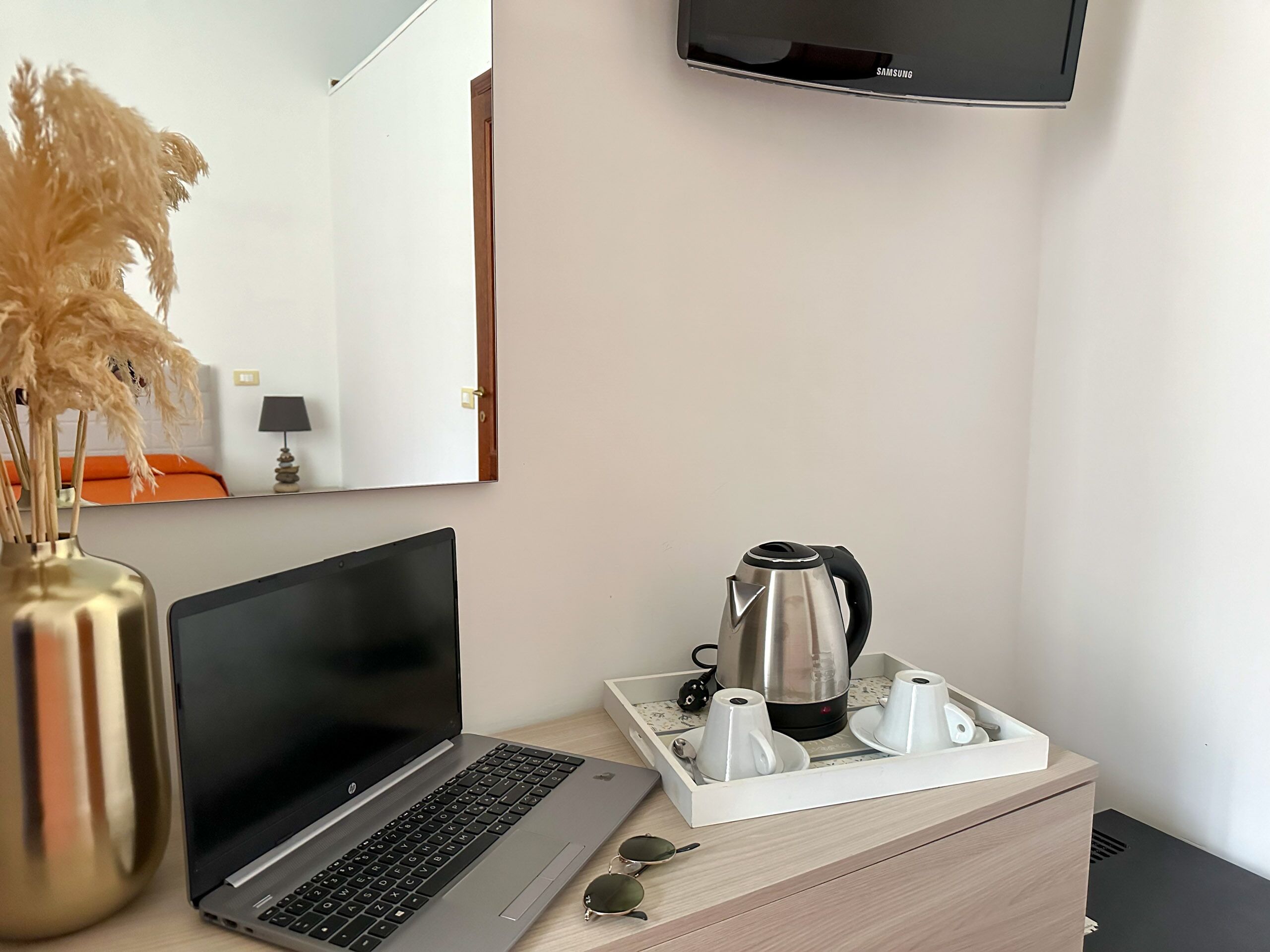Un espace de travail bien organisé, avec un ordinateur portable, une machine à café et un plateau contenant des tasses et des soucoupes.