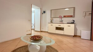 Una cucina moderna con pensili bianchi, un tavolo rotondo in vetro e una lampada a sospensione.