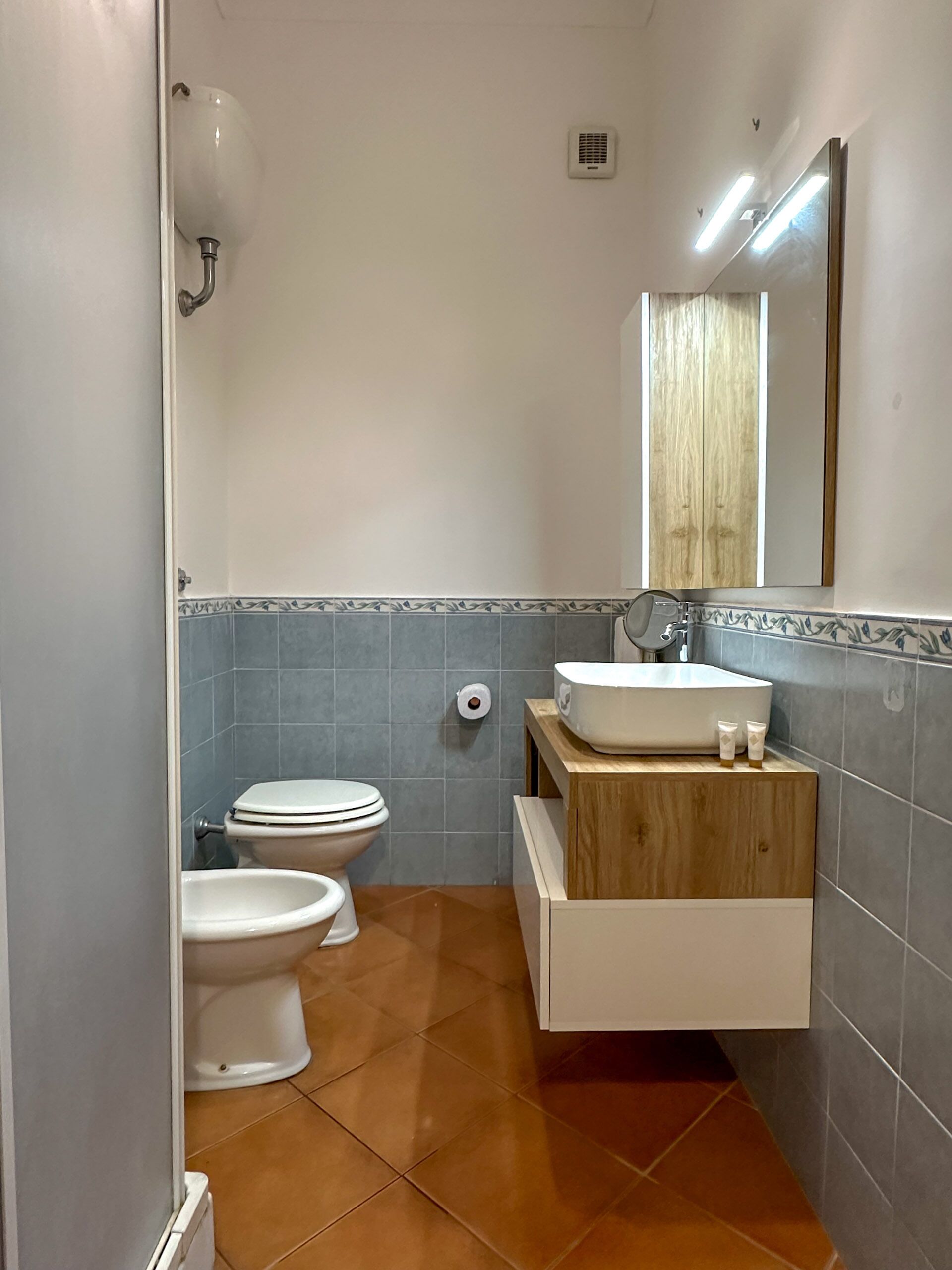 Ein Badezimmer mit zwei Toiletten, einem Waschbecken und einem Spiegel.