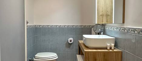Ein Badezimmer mit zwei Toiletten, einem Waschbecken und einem Spiegel.