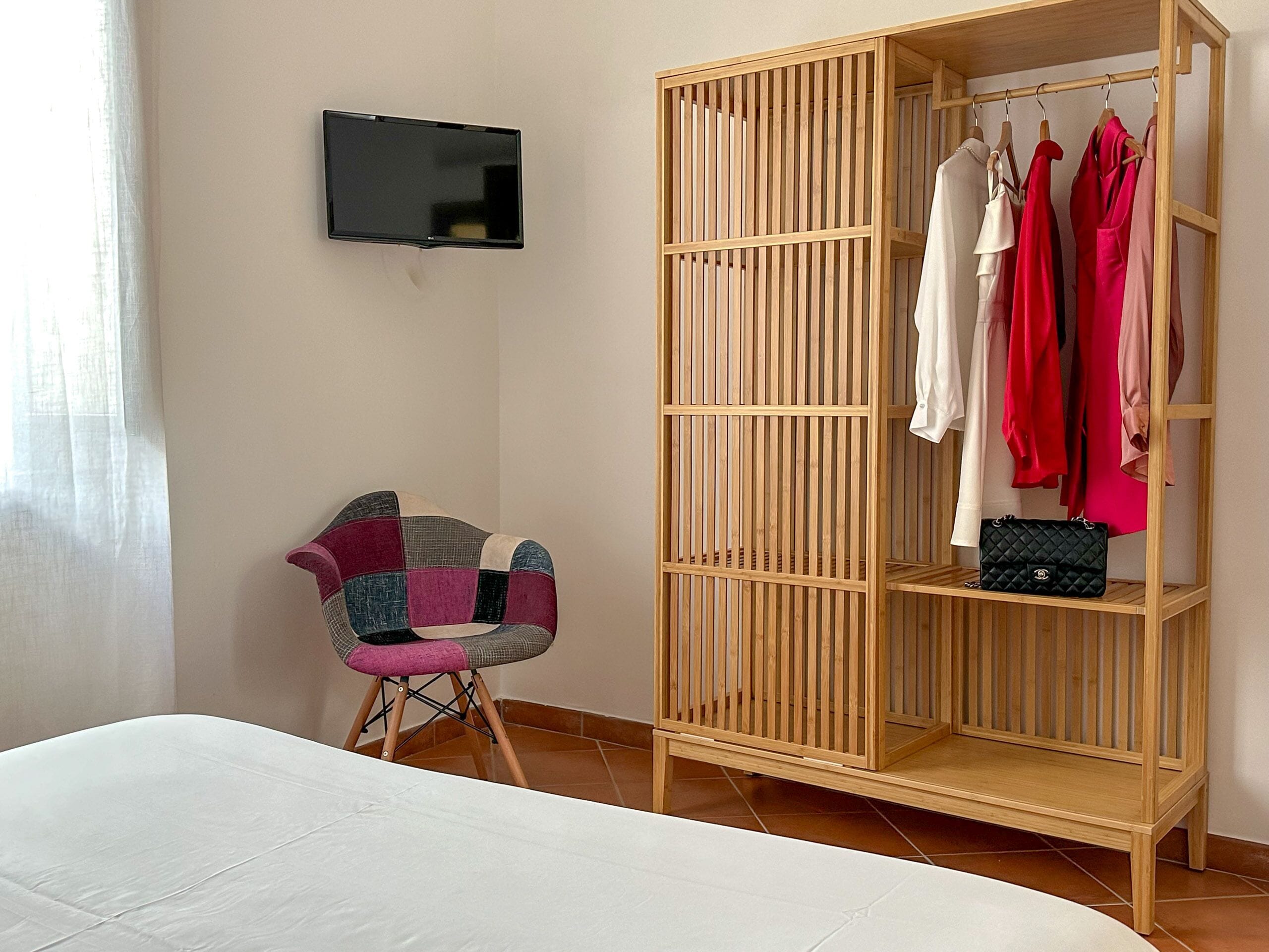Une chambre à coucher avec un lit, une armoire en bois, une télévision et une chaise.