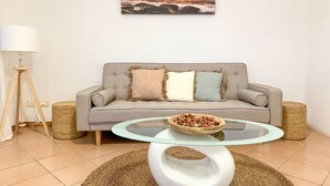 Un soggiorno con un divano grigio, un tavolino in vetro e un tappeto intrecciato.
