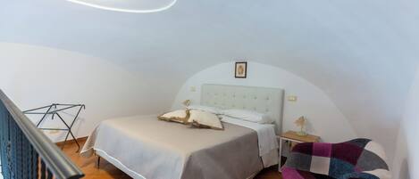 A bedroom with a bed, a chair, and a small table.