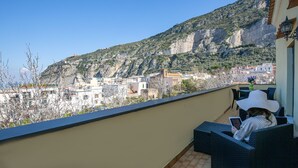 Un balcone con mobili in vimini, vista su edifici e una montagna.