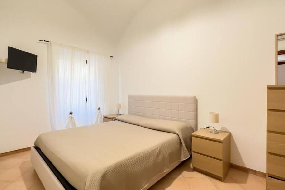A bedroom with a bed, bedside tables, a TV, and a dresser.