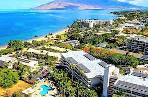 A resort with a pool, buildings, and a beach.