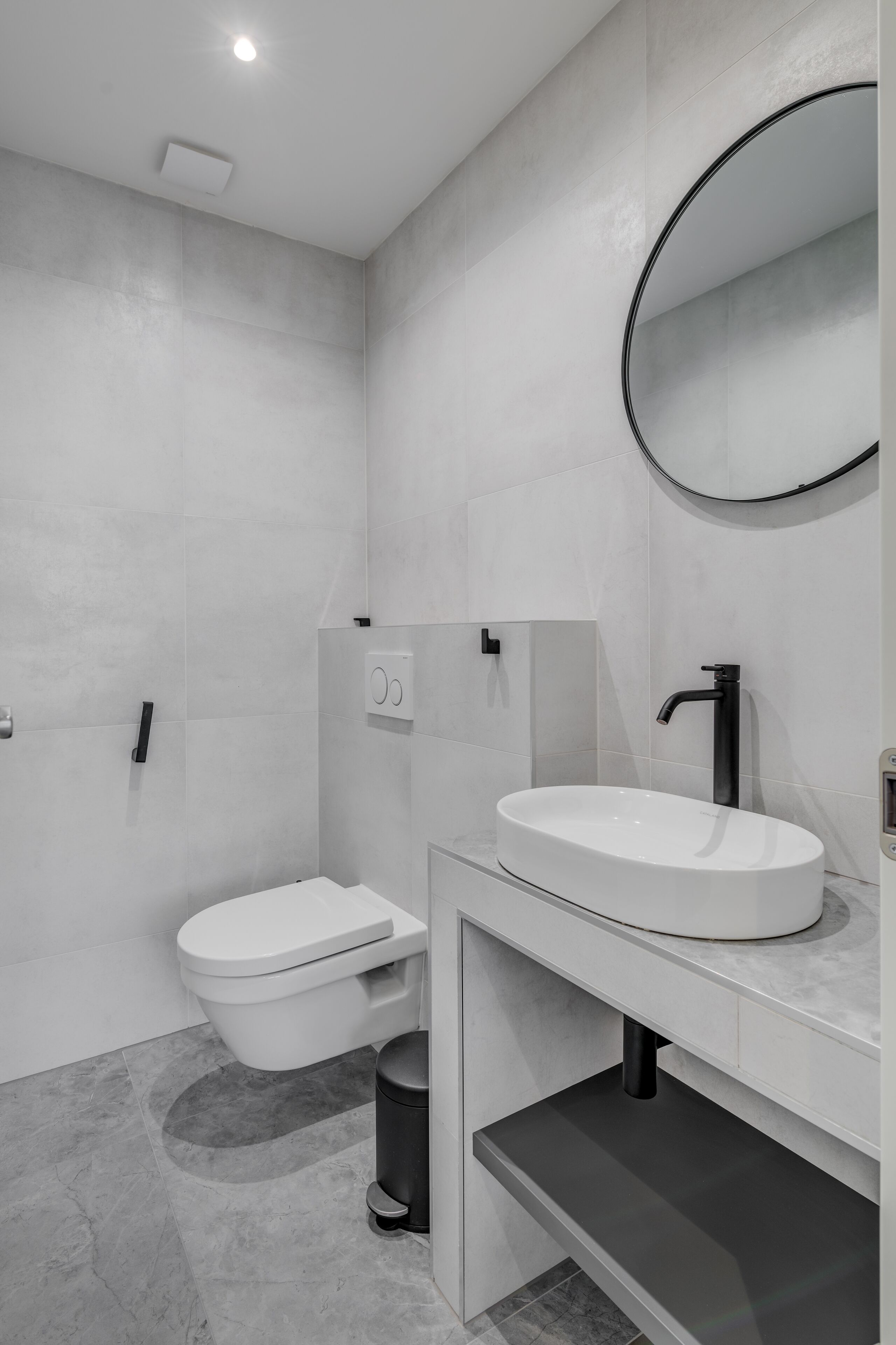 A modern bathroom with a toilet, sink, and mirror.