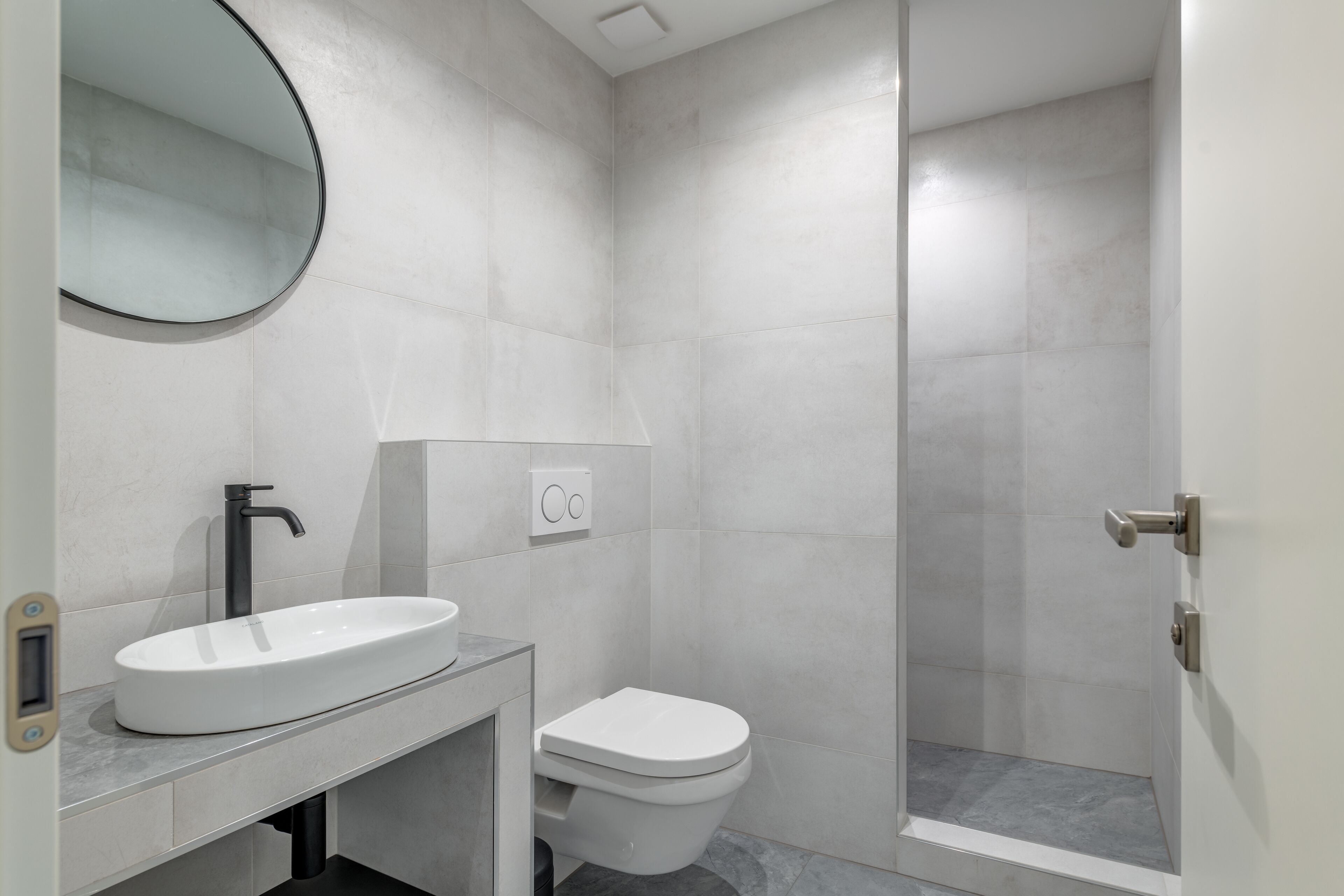 Un baño moderno con lavamanos blanco, inodoro y zona de ducha.