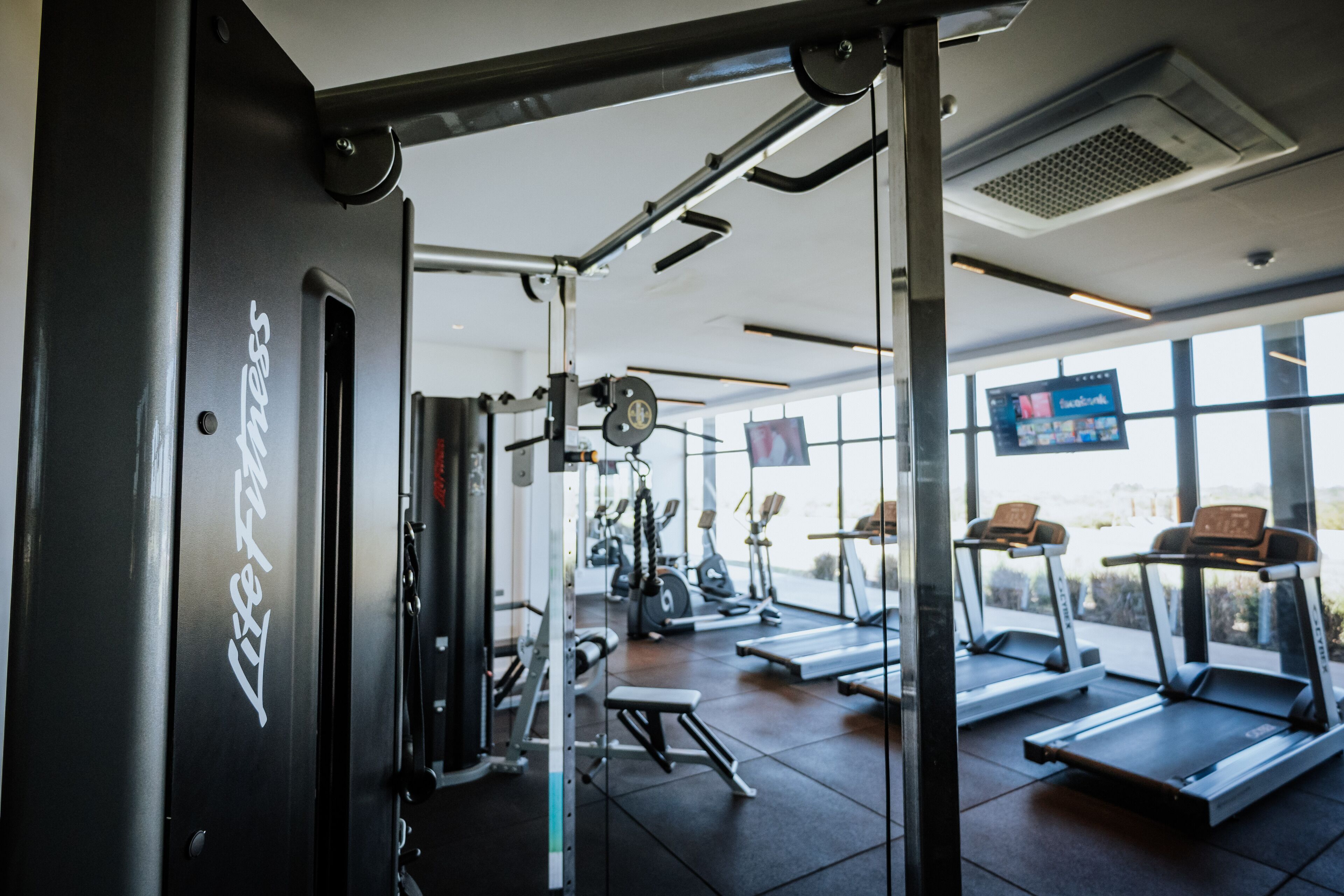 A gym with exercise equipment, treadmills, and a large window.