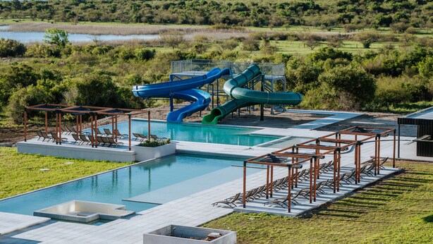 A pool area with slides, lounge chairs, and a view of the surrounding landscape.